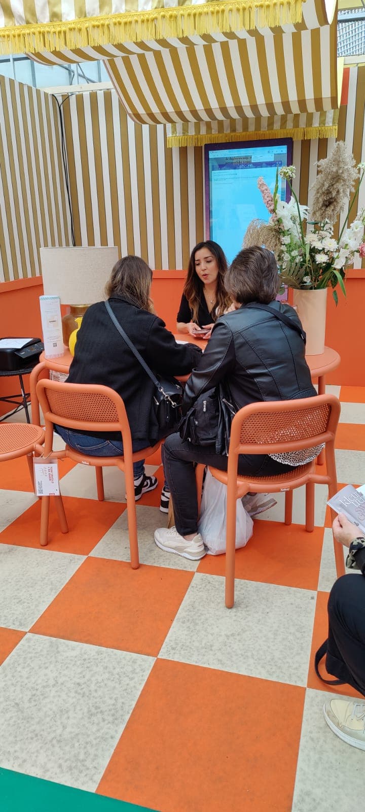 María Alejandra met twee cliënten bij de stand van het tijdschrift